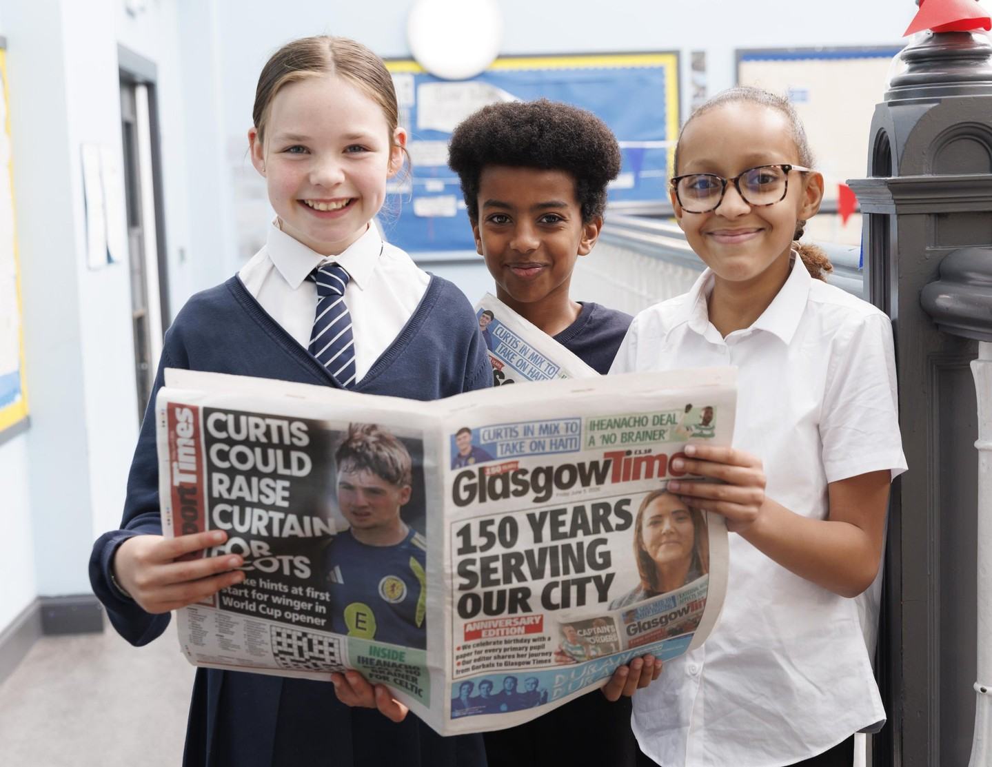 Pupils holding the Glasgow Times 150 Years front page